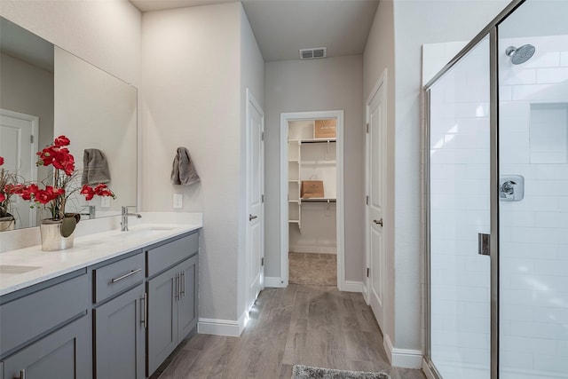 full bathroom featuring visible vents, a stall shower, a sink, wood finished floors, and a spacious closet