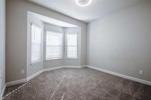 carpeted empty room featuring baseboards