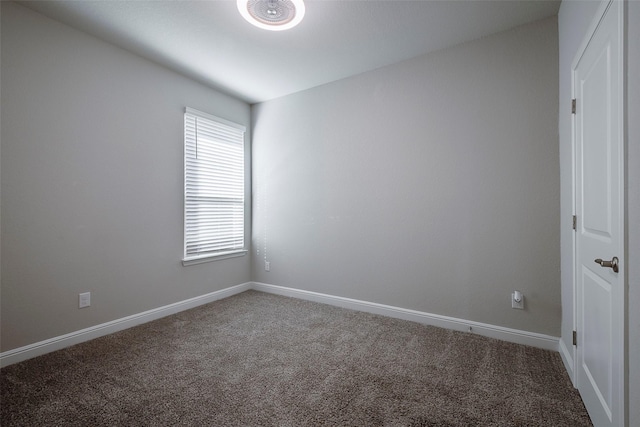 empty room featuring carpet and baseboards