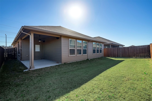 back of property with a fenced backyard, a patio area, a lawn, and ceiling fan