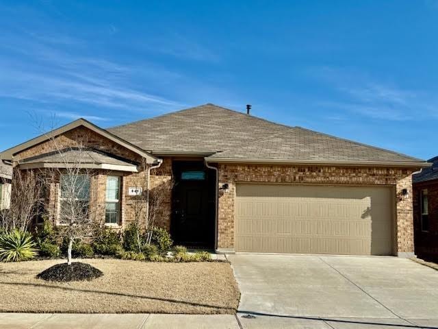 single story home with brick siding, a garage, driveway, and roof with shingles