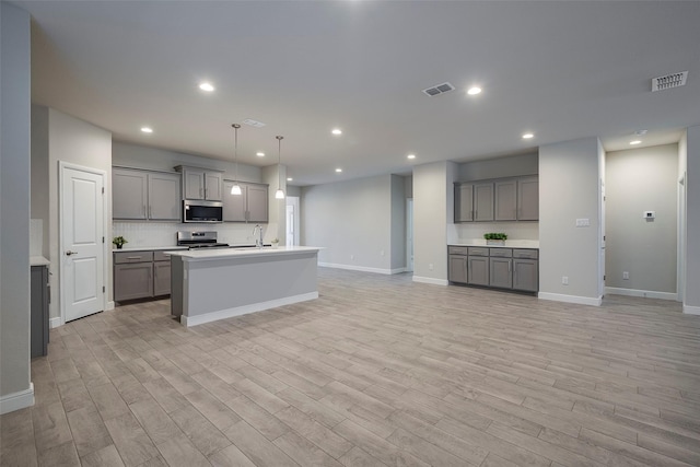 kitchen featuring visible vents, gray cabinetry, and stainless steel appliances