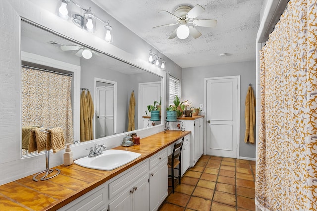 full bathroom featuring a ceiling fan, a textured ceiling, and vanity