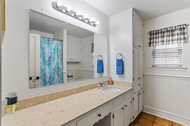 bathroom featuring a wainscoted wall, vanity, a shower with shower curtain, and tile patterned floors