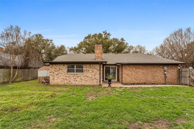 rear view of property featuring brick siding, a yard, a chimney, roof with shingles, and a fenced backyard