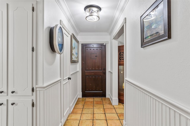 doorway featuring a wainscoted wall, crown molding, and light tile patterned flooring