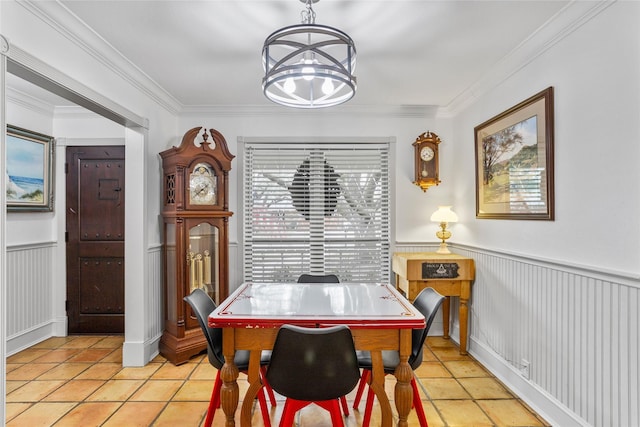 dining area with light tile patterned floors, wainscoting, crown molding, and an inviting chandelier