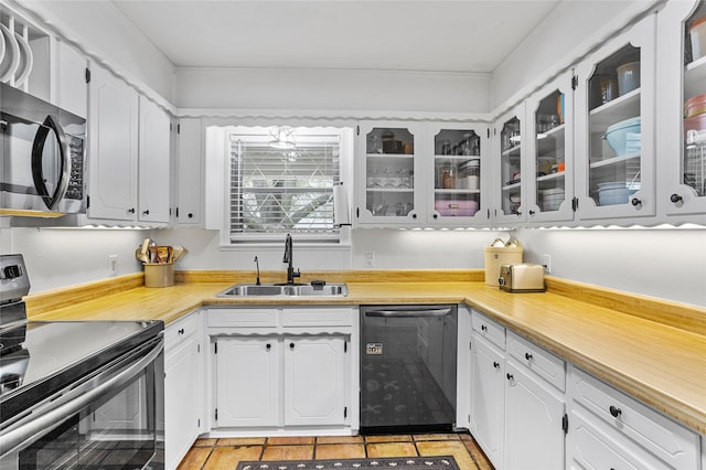 kitchen with light countertops, appliances with stainless steel finishes, glass insert cabinets, white cabinets, and a sink