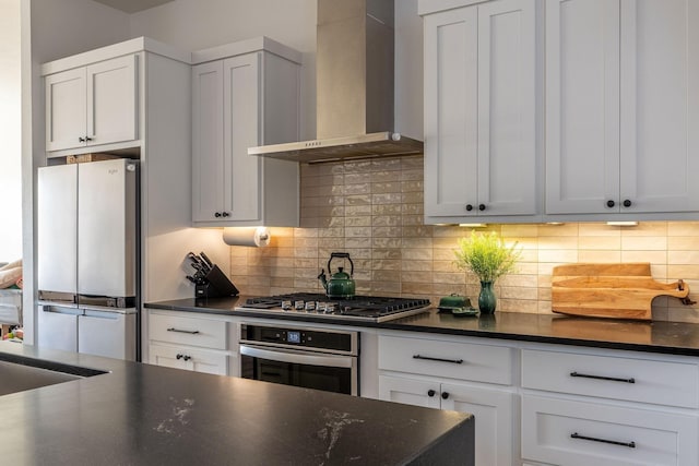 kitchen with white cabinets, wall chimney range hood, stainless steel appliances, and decorative backsplash