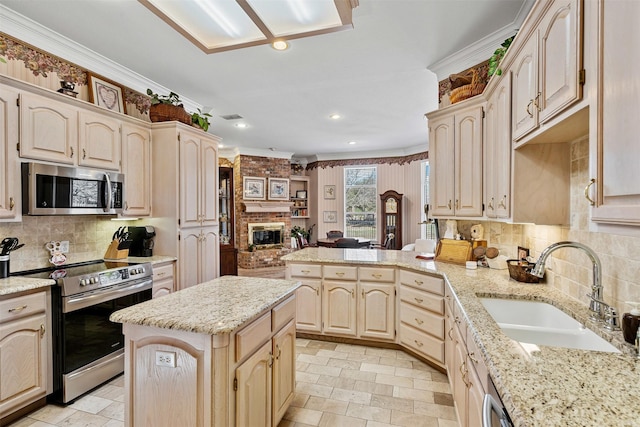 kitchen featuring stainless steel appliances, stone tile flooring, a brick fireplace, a sink, and a peninsula