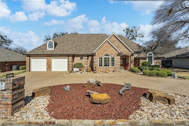 view of front of home with a garage, concrete driveway, brick siding, and a shingled roof