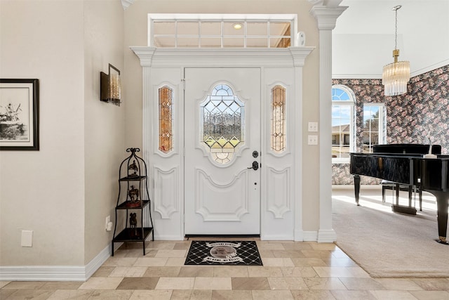 entryway with light carpet, a high ceiling, baseboards, stone finish flooring, and decorative columns