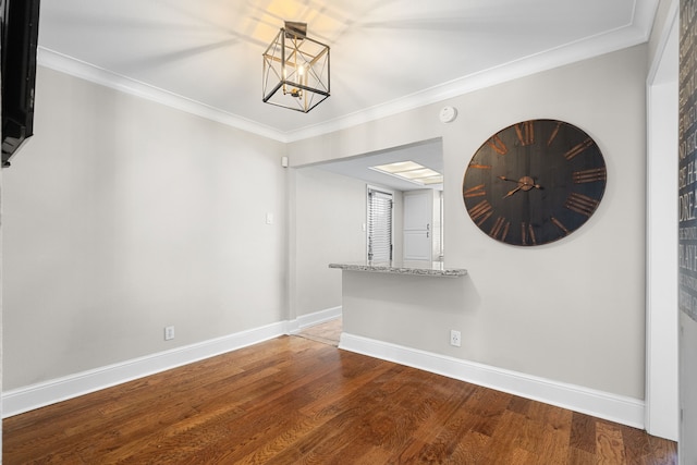 unfurnished dining area featuring baseboards, a notable chandelier, wood finished floors, and crown molding