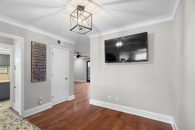 interior space featuring visible vents, crown molding, baseboards, and wood finished floors