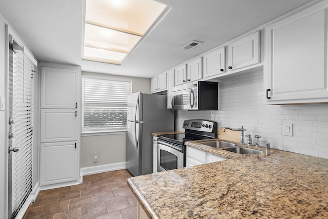 kitchen featuring stainless steel appliances, a sink, visible vents, white cabinetry, and backsplash