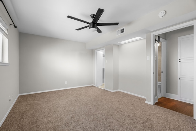 carpeted spare room featuring baseboards, visible vents, and a ceiling fan