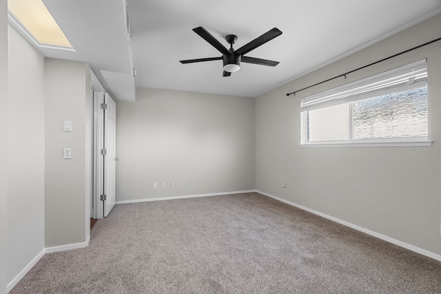 carpeted empty room featuring ceiling fan and baseboards