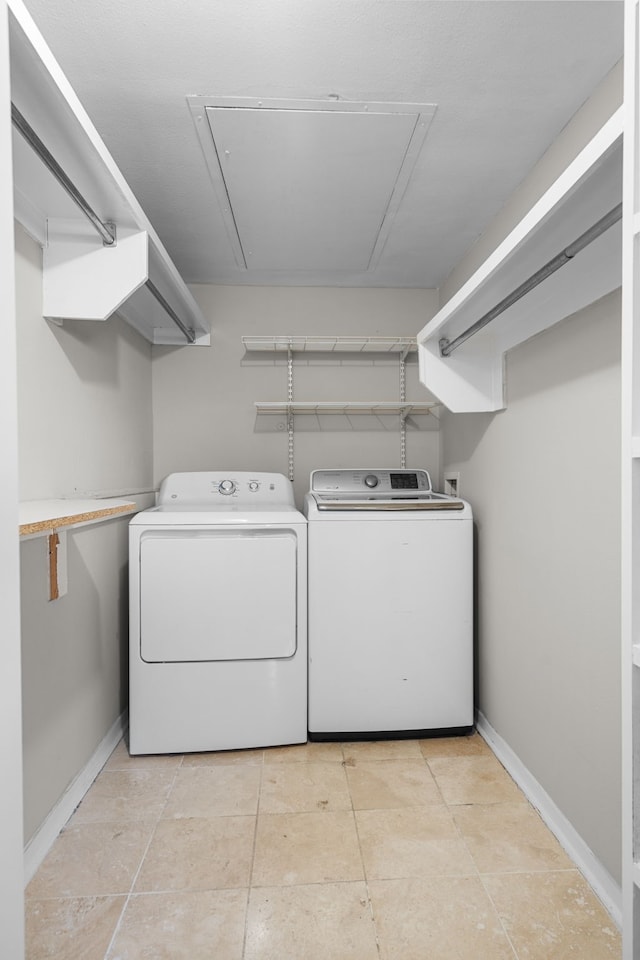 washroom featuring washing machine and clothes dryer, light tile patterned floors, attic access, laundry area, and baseboards