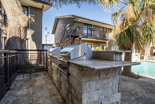 view of patio / terrace with stairway, area for grilling, a grill, and a fenced in pool