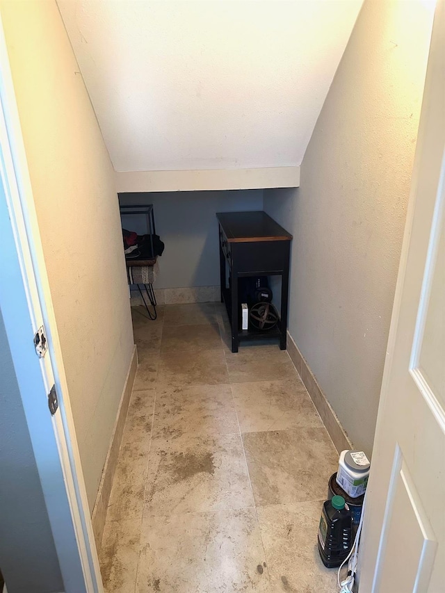 corridor featuring vaulted ceiling and baseboards