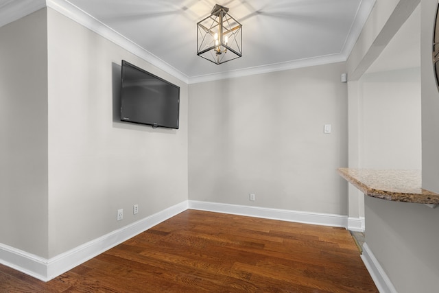 unfurnished dining area featuring ornamental molding, an inviting chandelier, baseboards, and wood finished floors