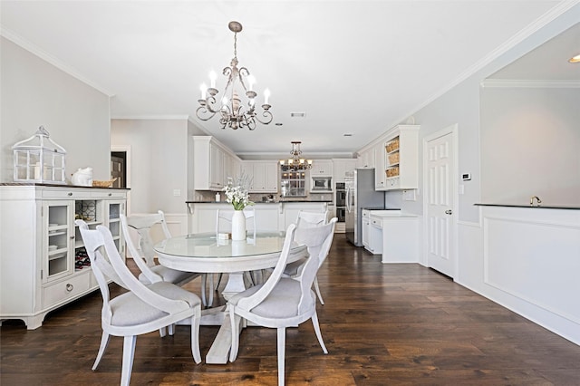 dining room with a notable chandelier, a wainscoted wall, dark wood-style flooring, visible vents, and ornamental molding