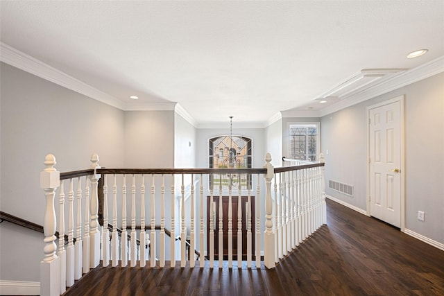 hallway with baseboards, visible vents, wood finished floors, crown molding, and an upstairs landing