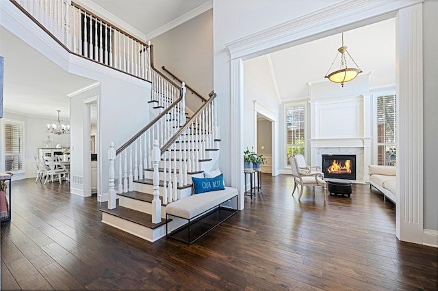 foyer entrance with stairs, dark wood-type flooring, a towering ceiling, and a high end fireplace