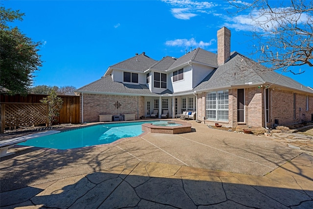 view of swimming pool featuring a pool with connected hot tub, fence, and a patio