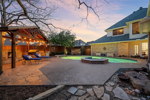 patio terrace at dusk featuring a fenced backyard, a pool with connected hot tub, and a gazebo