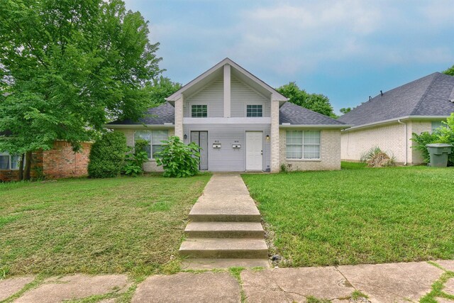 view of front of property with a front yard, brick siding, and roof with shingles