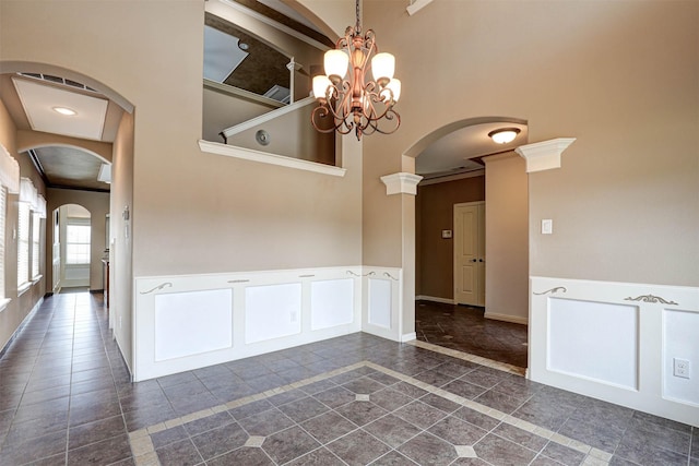 14124 Rodeo Daze Dr, Fort Worth, TX 76052 - empty room featuring arched walkways, a chandelier, a wainscoted wall, baseboards, and a towering ceiling