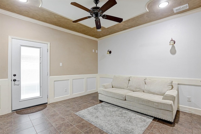 living room featuring a wainscoted wall, visible vents, crown molding, and a decorative wall