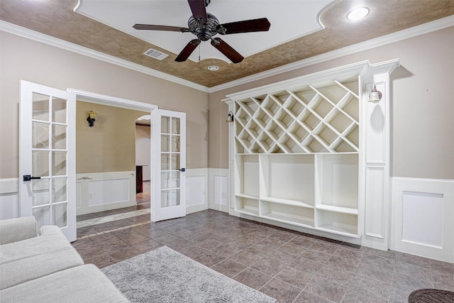 interior space featuring french doors, visible vents, a wainscoted wall, and crown molding