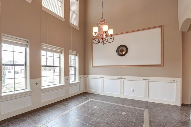 14124 Rodeo Daze Dr, Fort Worth, TX 76052 - unfurnished dining area featuring wainscoting, an inviting chandelier, plenty of natural light, and a towering ceiling