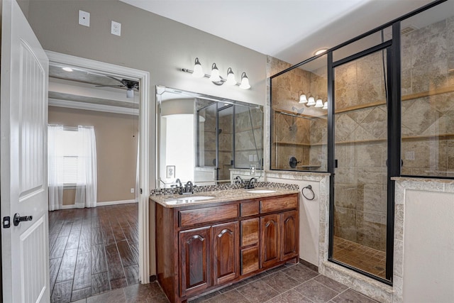 bathroom featuring double vanity, a stall shower, baseboards, and a sink