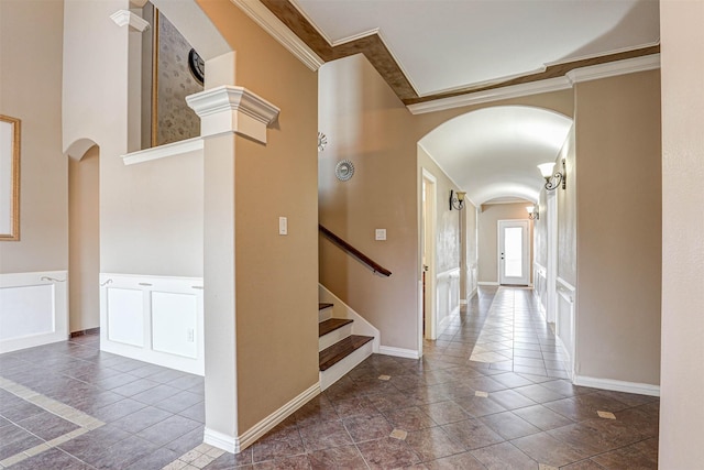 hall with arched walkways, stairway, ornamental molding, tile patterned floors, and a decorative wall