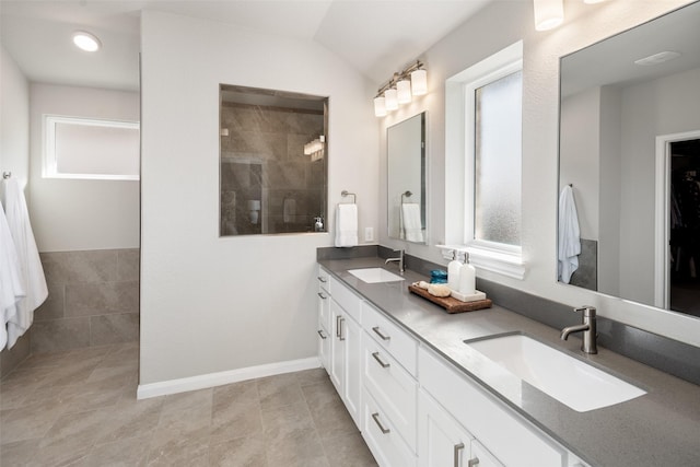 bathroom featuring vaulted ceiling, double vanity, a sink, and walk in shower