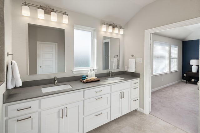 bathroom featuring vaulted ceiling, double vanity, and a sink