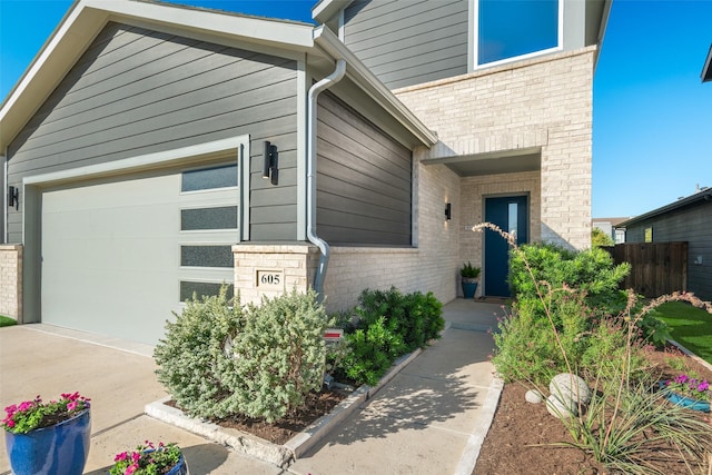 view of front of home with an attached garage, fence, and brick siding