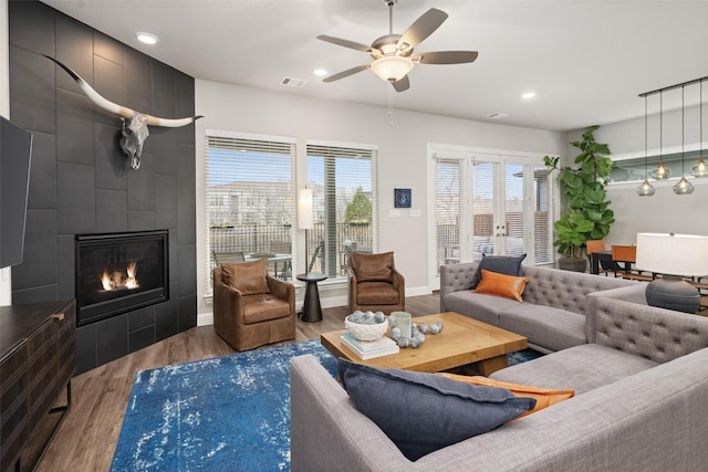 living room with recessed lighting, visible vents, wood finished floors, and a tile fireplace