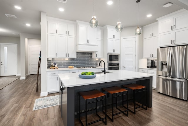 kitchen with wood finished floors, light countertops, appliances with stainless steel finishes, and a kitchen bar