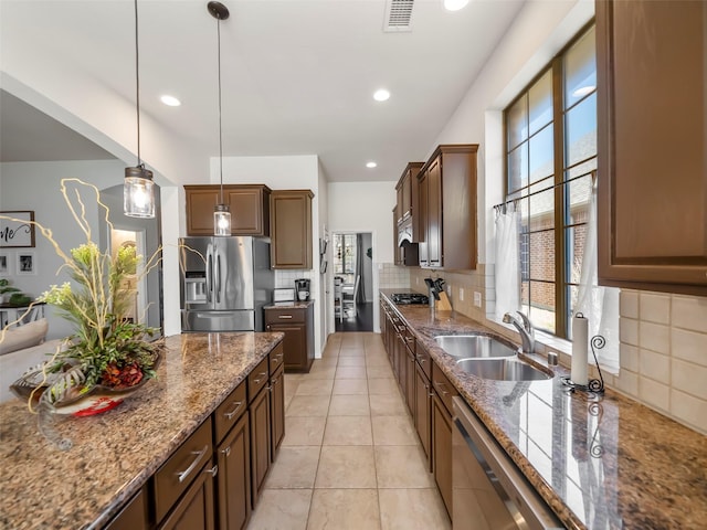 kitchen featuring tasteful backsplash, visible vents, hanging light fixtures, appliances with stainless steel finishes, and a sink