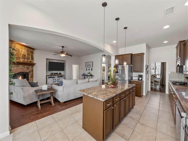 kitchen featuring arched walkways, stainless steel appliances, tasteful backsplash, visible vents, and light tile patterned flooring