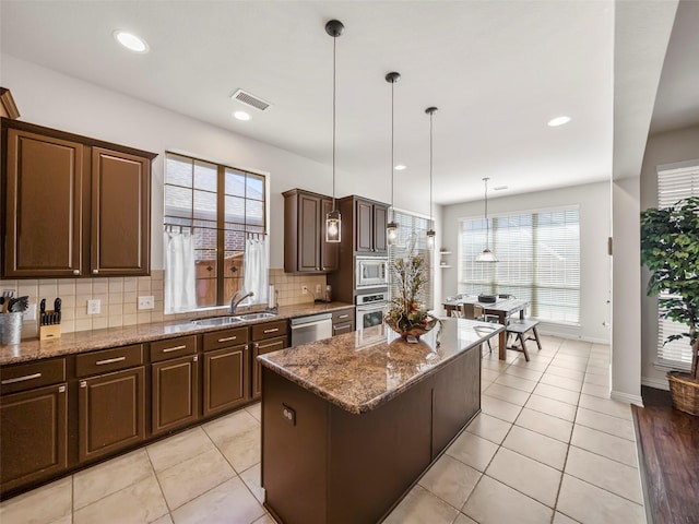 kitchen featuring a sink, visible vents, a healthy amount of sunlight, appliances with stainless steel finishes, and backsplash