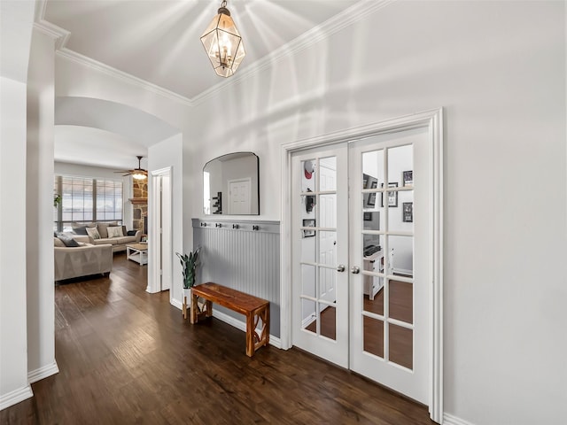 doorway featuring arched walkways, dark wood-type flooring, crown molding, french doors, and ceiling fan with notable chandelier