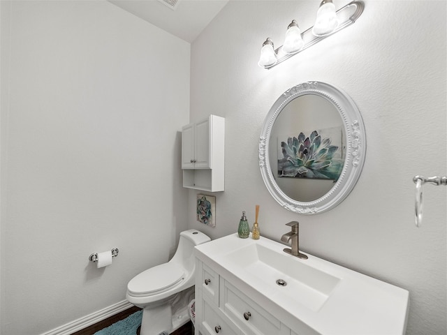 half bathroom with vanity, toilet, and baseboards