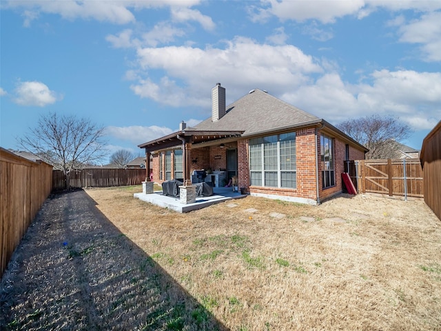 back of property with brick siding, a chimney, a patio area, and a fenced backyard