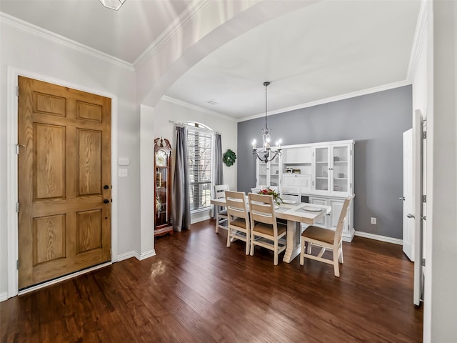 dining room featuring arched walkways, baseboards, ornamental molding, dark wood finished floors, and an inviting chandelier