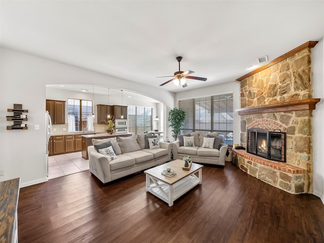 living room with a wealth of natural light, visible vents, a fireplace, and wood finished floors